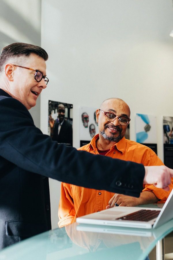 Two businessmen in office, examining laptop.
